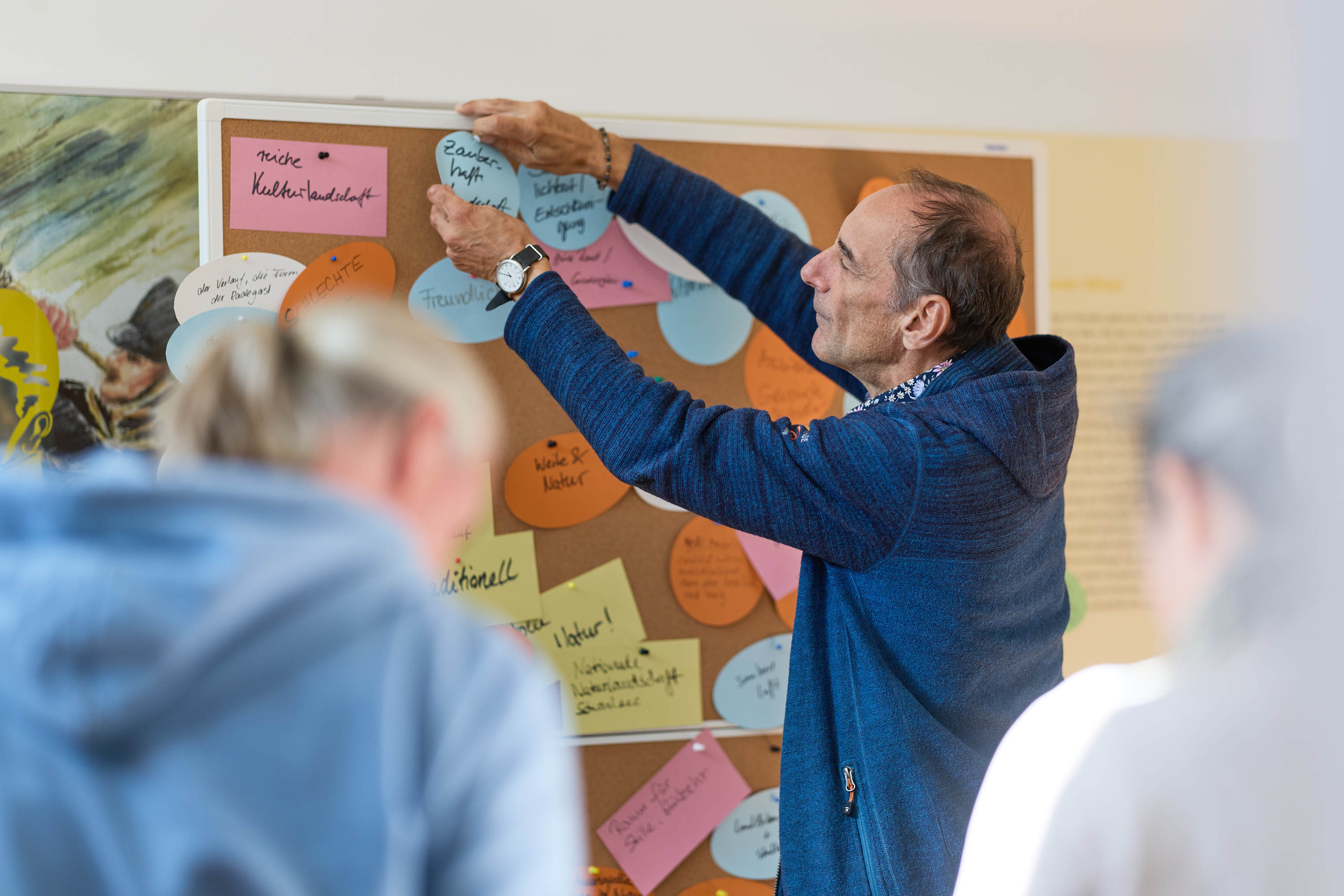 Ein Mann hängt ein Notizkärtchen an eine Pinnwand