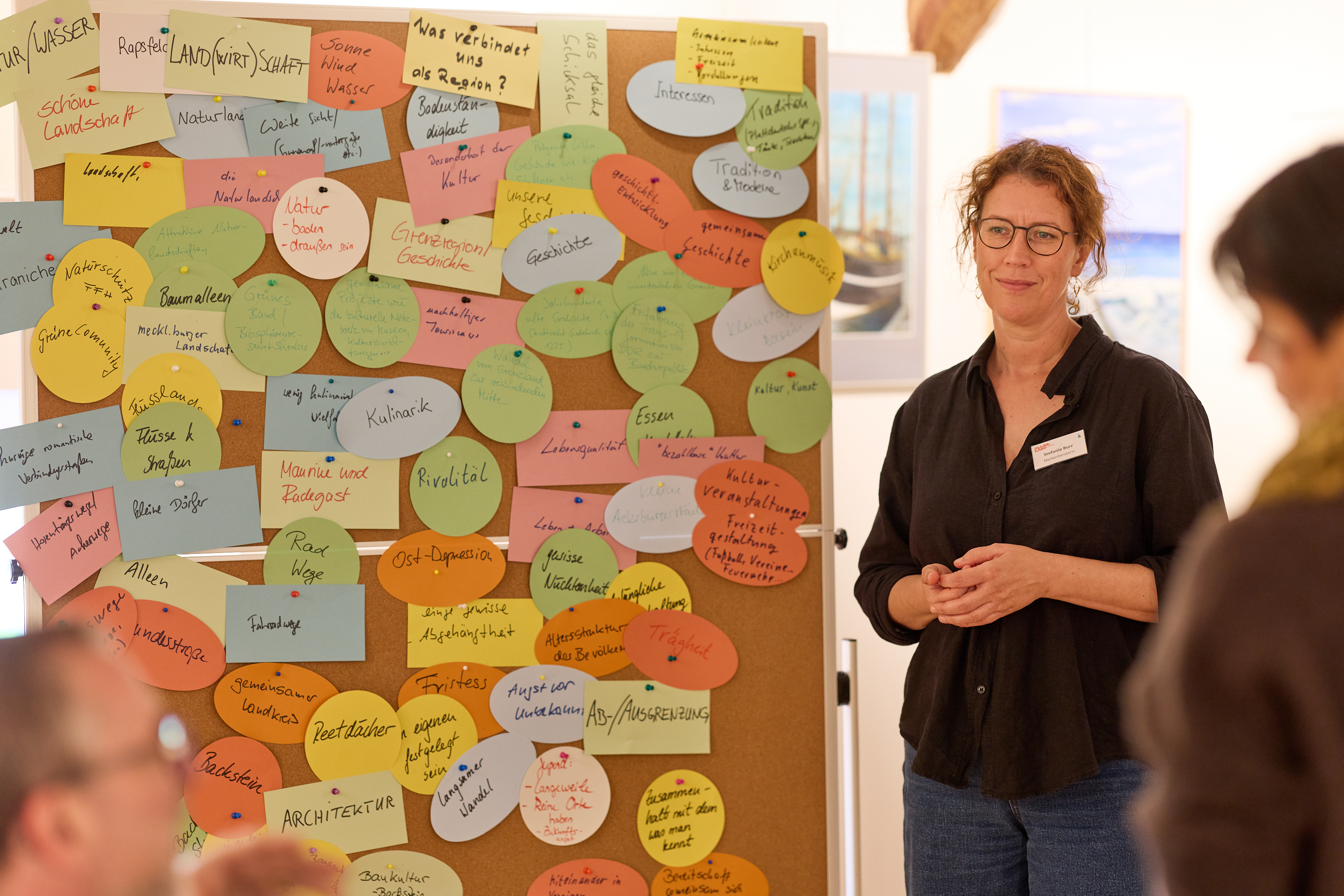 eine Frau steht neben einer Pinnwand voller bunter und beschriebener Moderationskarten