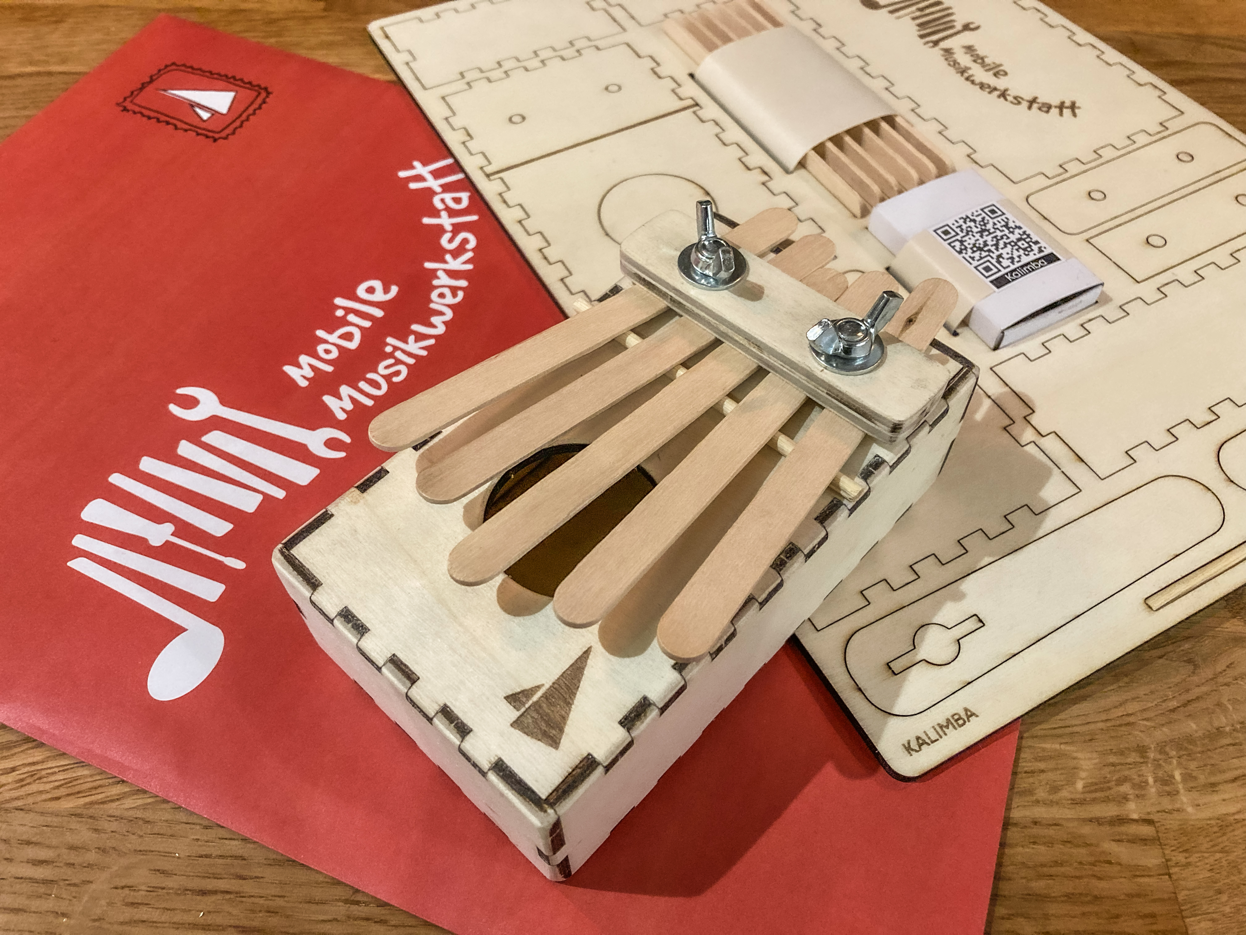 eine zusammengebaute Kalimba liegt auf einem Bausatz zum selberbauen